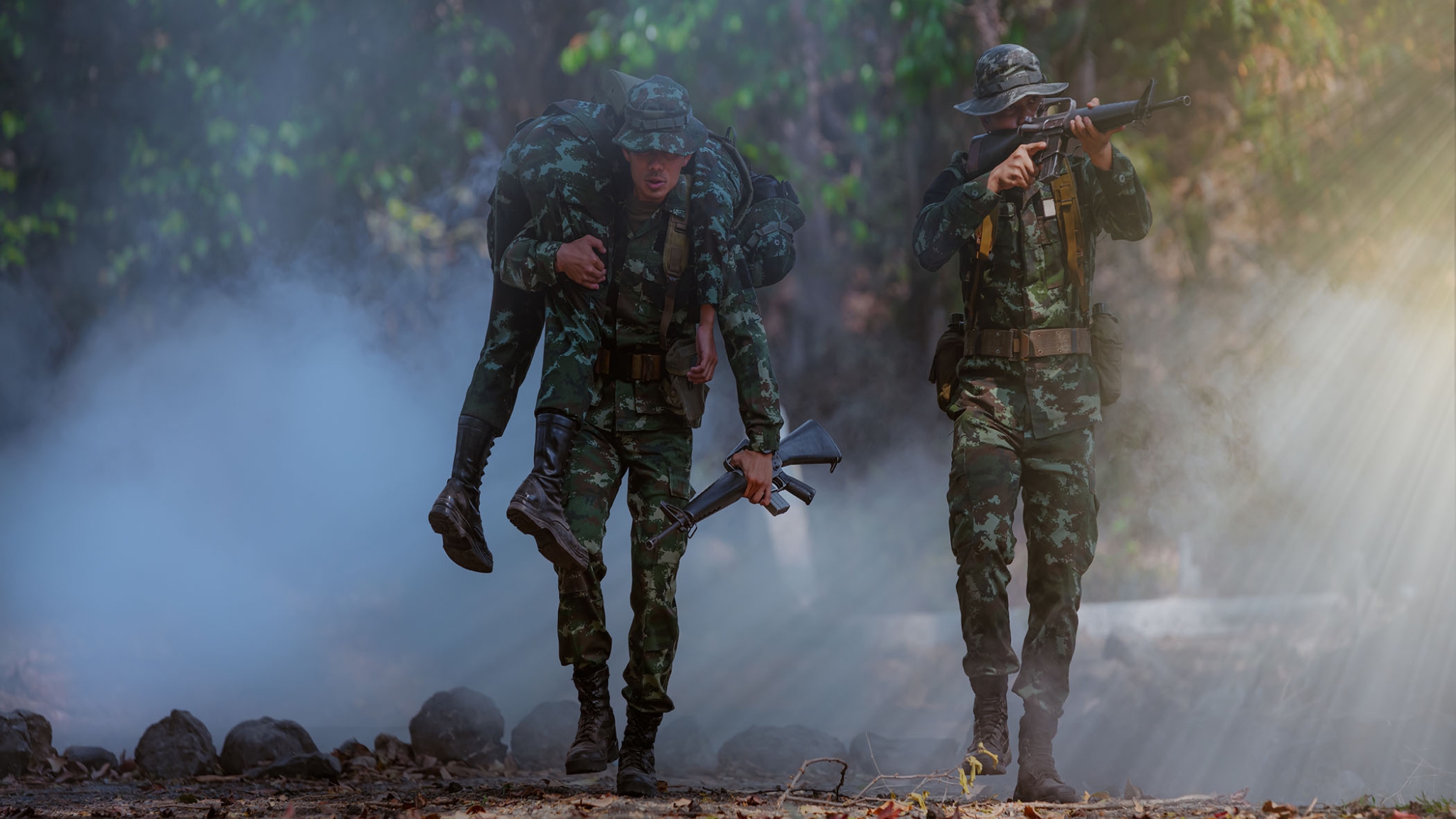 A soldier carries another who is injured in combat