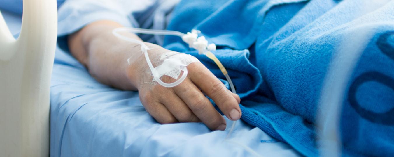 A patient with an IV lies in a hospital bed