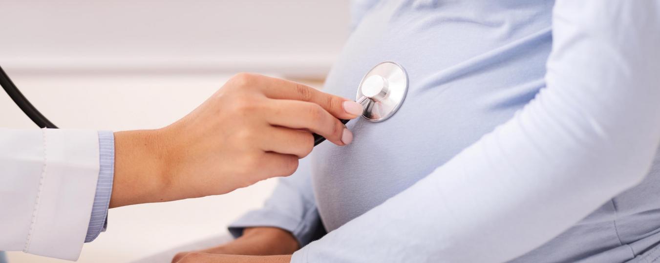 Health care provider uses stethoscope on pregnant woman's belly