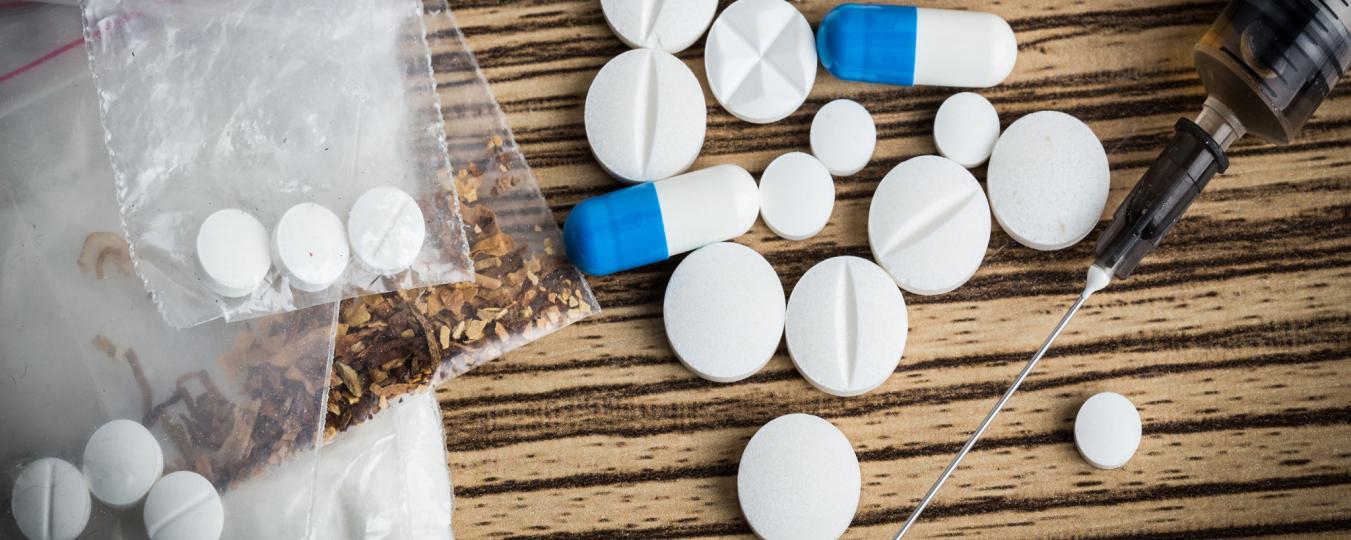 White and blue pills and other illegal drugs on a table