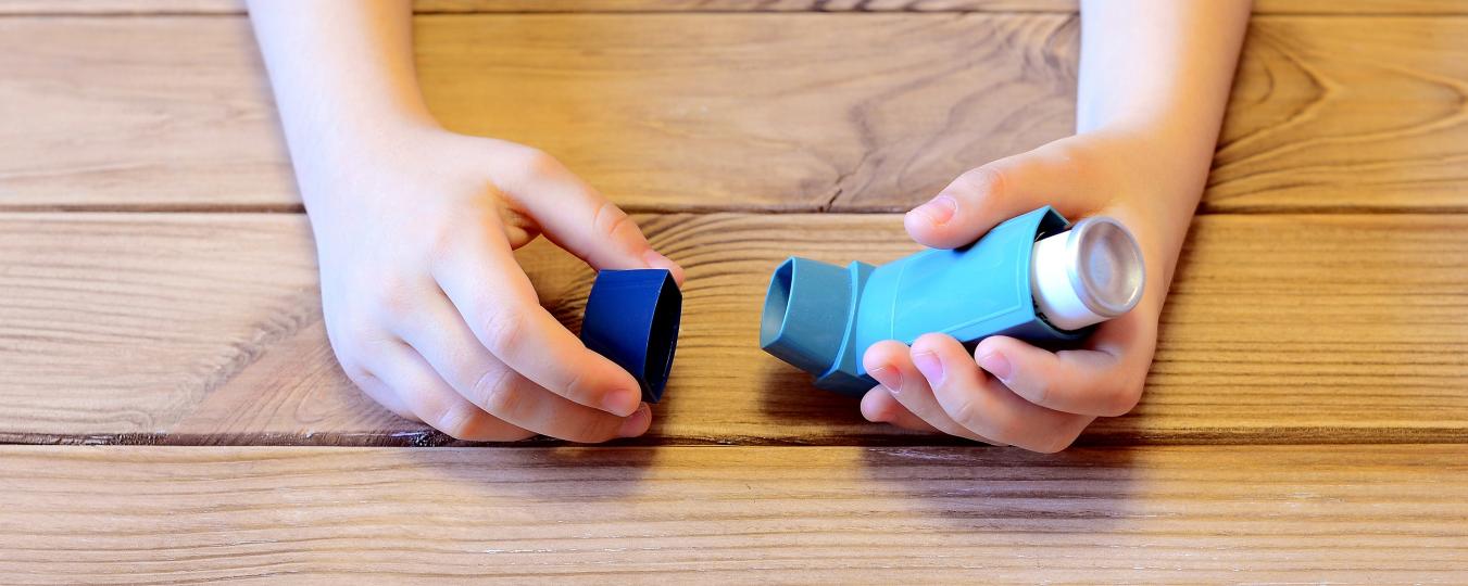 A child holds a blue inhaler over a table