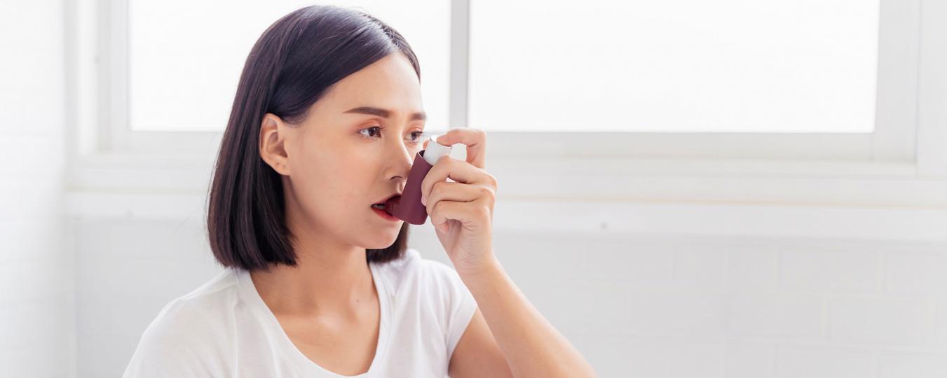 A woman takes a breath from an inhaler