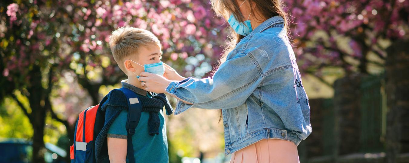 Woman fixing boy's mask before school