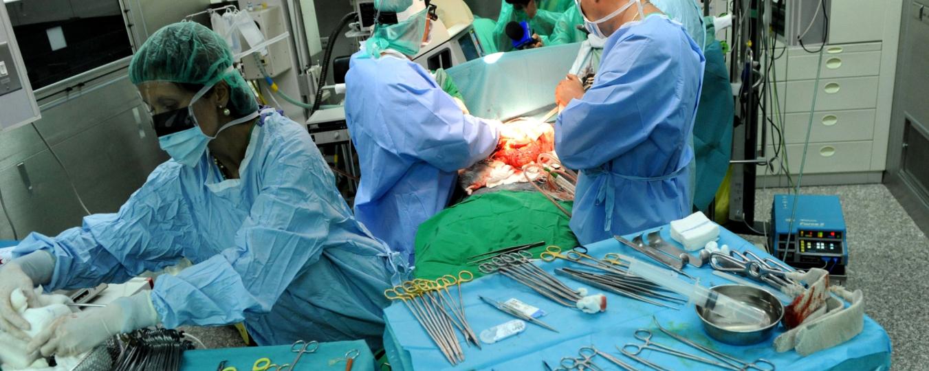 Surgeons in an operating room look at a patient while tools sit on a table