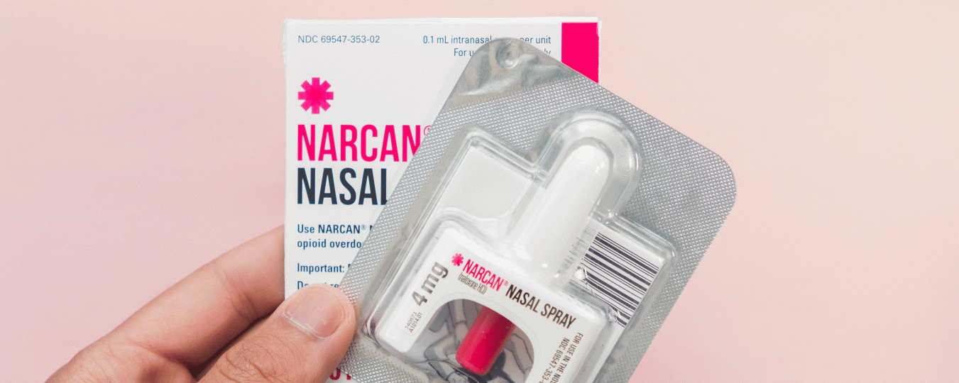 A person holds up a naloxone nasal spray dispenser