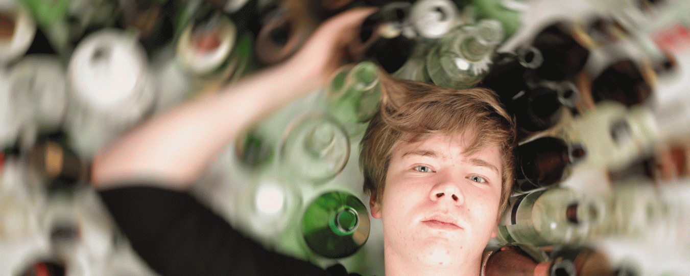 A teenager lays among glass bottles 