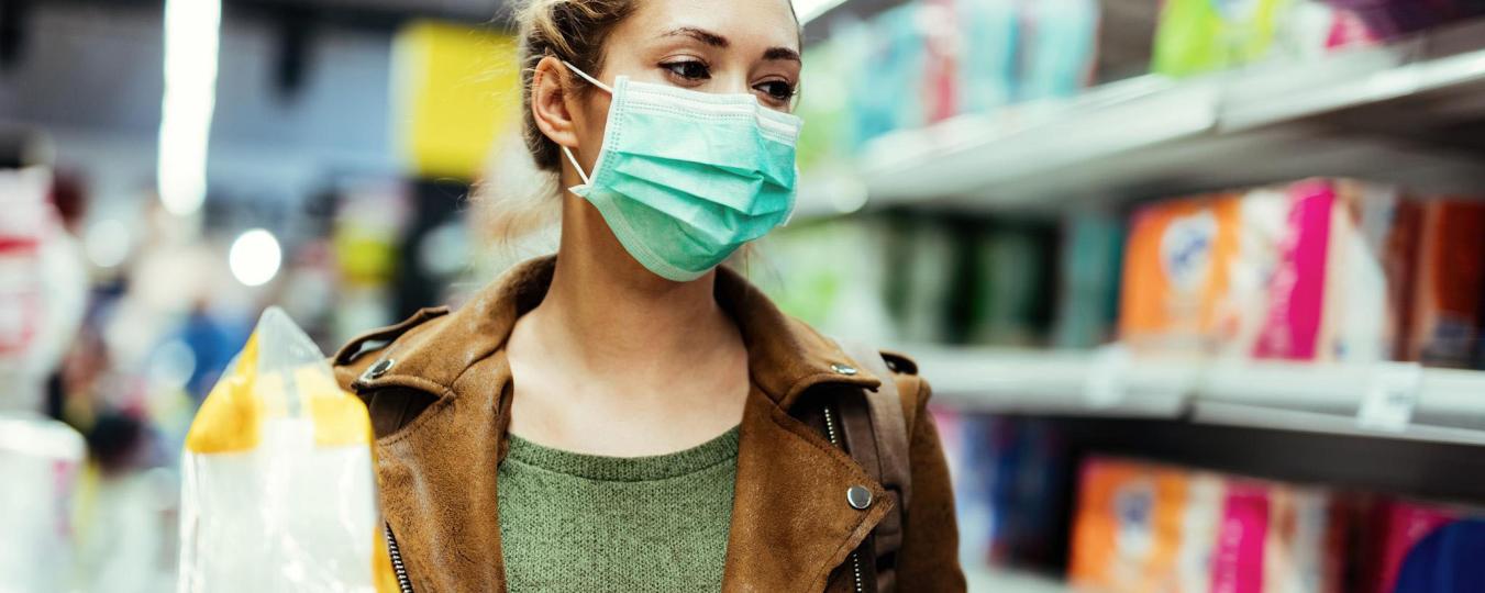 Woman grocery shopping in a mask