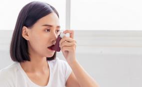A woman takes a breath from an inhaler
