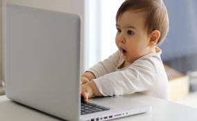 A baby stares at a laptop screen