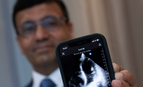 A doctor holds up a phone that shows a scan of a heart muscle