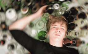 A teenager lays among glass bottles 